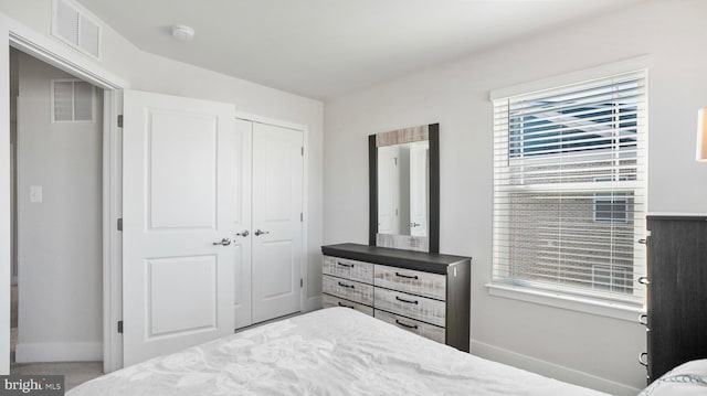 bedroom featuring multiple windows, a closet, visible vents, and baseboards