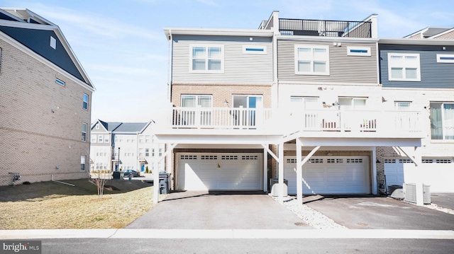 multi unit property featuring driveway, central air condition unit, an attached garage, and a front yard