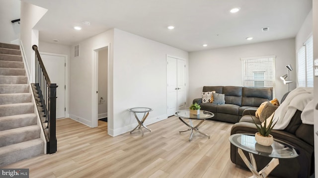 living area featuring visible vents, baseboards, stairs, light wood-type flooring, and recessed lighting