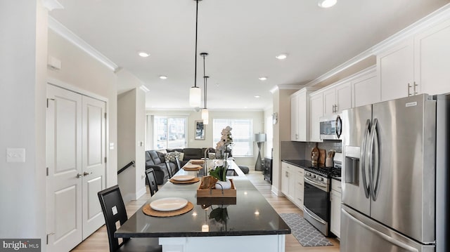 kitchen with ornamental molding, open floor plan, stainless steel appliances, light wood-style floors, and white cabinetry