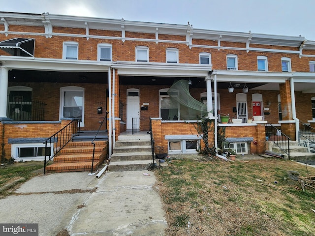 townhome / multi-family property with covered porch and brick siding