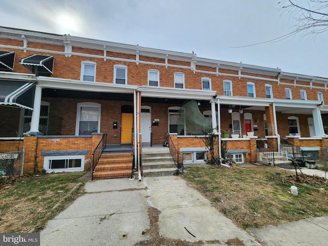 view of property featuring a porch and brick siding