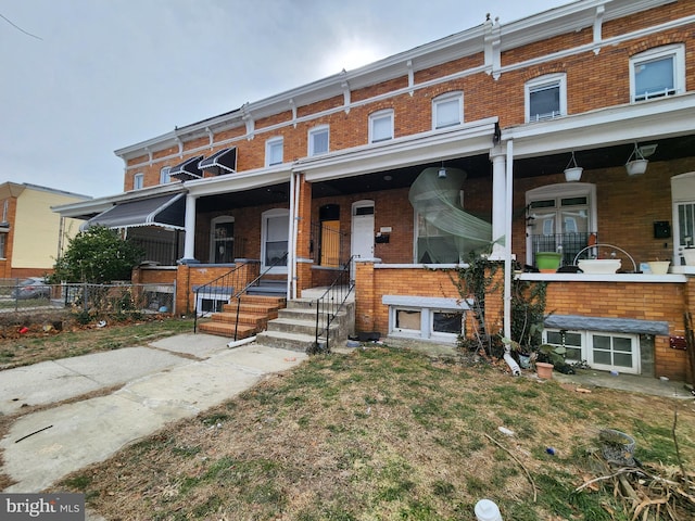 townhome / multi-family property with brick siding and a porch