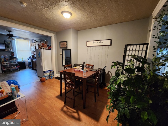 dining space with a textured ceiling, ceiling fan, and wood finished floors