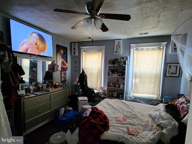 bedroom with ceiling fan, multiple windows, visible vents, and a textured ceiling