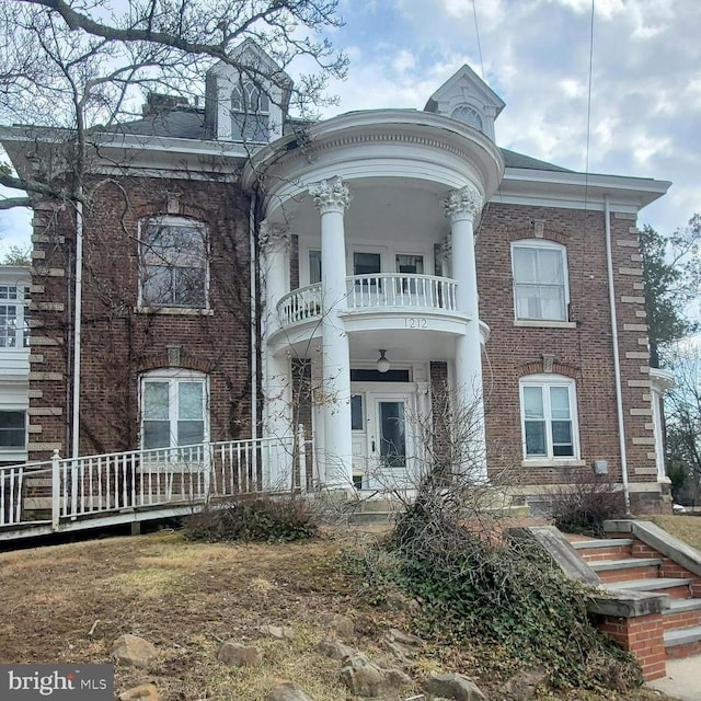 greek revival house featuring a balcony and brick siding