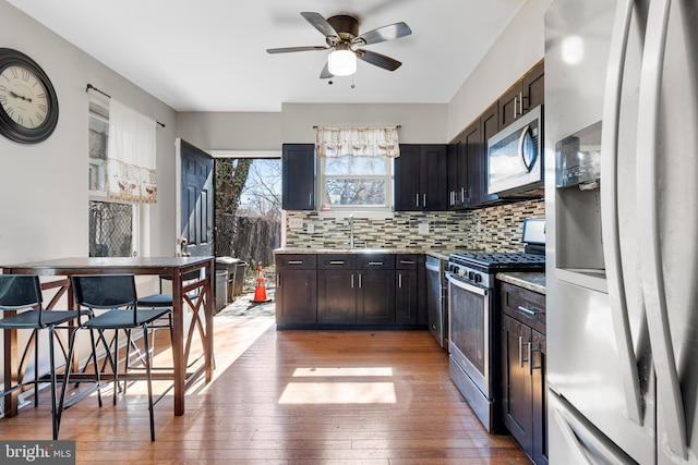 kitchen featuring a sink, light countertops, appliances with stainless steel finishes, light wood-type flooring, and backsplash