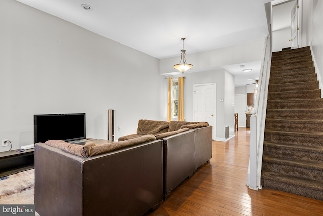 living area featuring wood-type flooring, stairs, and baseboards