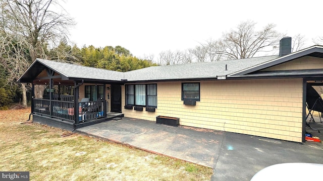 exterior space with a patio area, a chimney, and roof with shingles