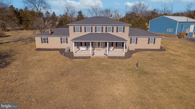 view of front of home featuring a patio area, roof with shingles, and a front yard