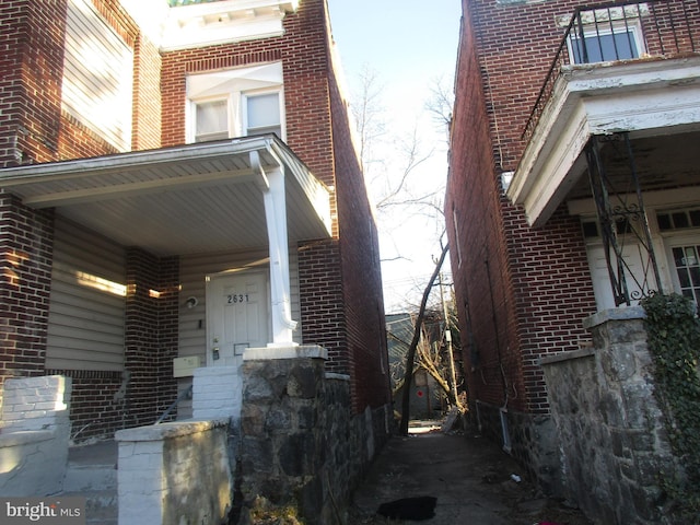 view of property exterior featuring covered porch and brick siding