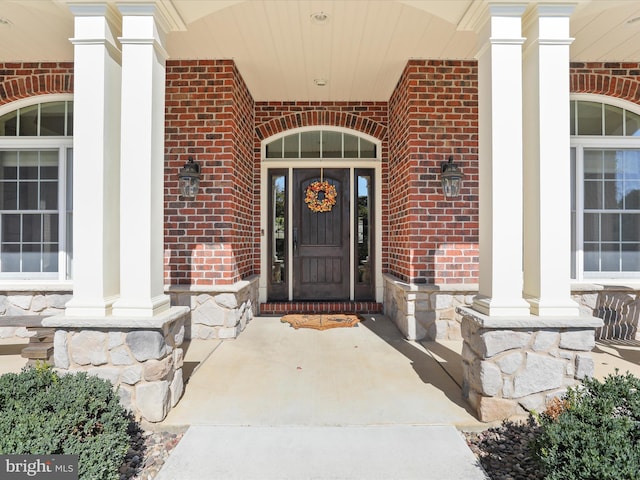 property entrance with a porch, stone siding, and brick siding