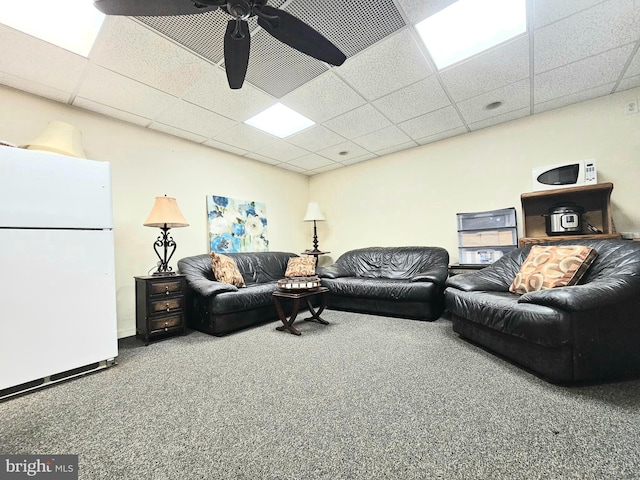 carpeted living area featuring ceiling fan and a drop ceiling