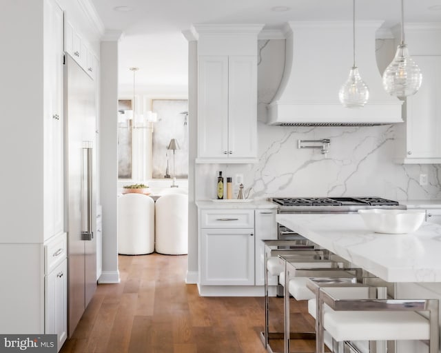 kitchen with stainless steel gas stovetop, wood finished floors, custom range hood, and ornamental molding