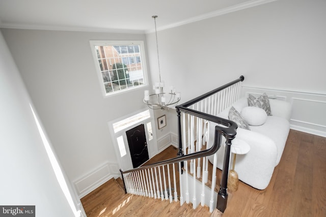 staircase with a chandelier, crown molding, and wood finished floors