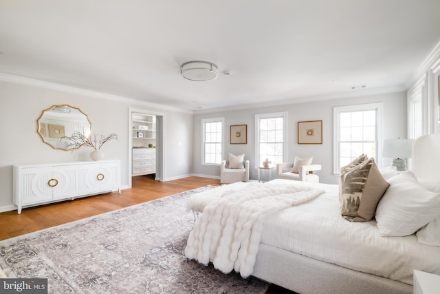 bedroom featuring visible vents, wood finished floors, baseboards, and ornamental molding