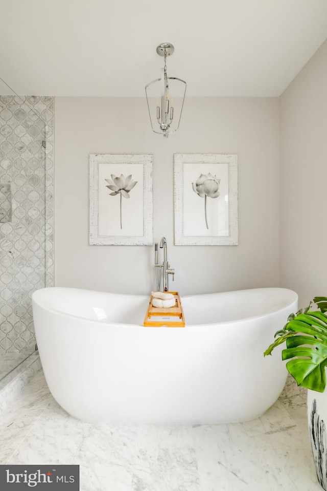 bathroom featuring a chandelier, marble finish floor, and a freestanding bath
