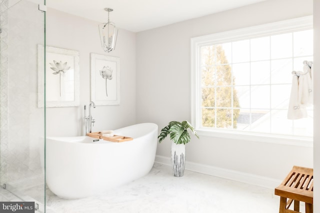 full bath with baseboards, a soaking tub, and marble finish floor