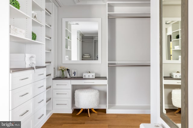 walk in closet with wood finished floors and built in desk
