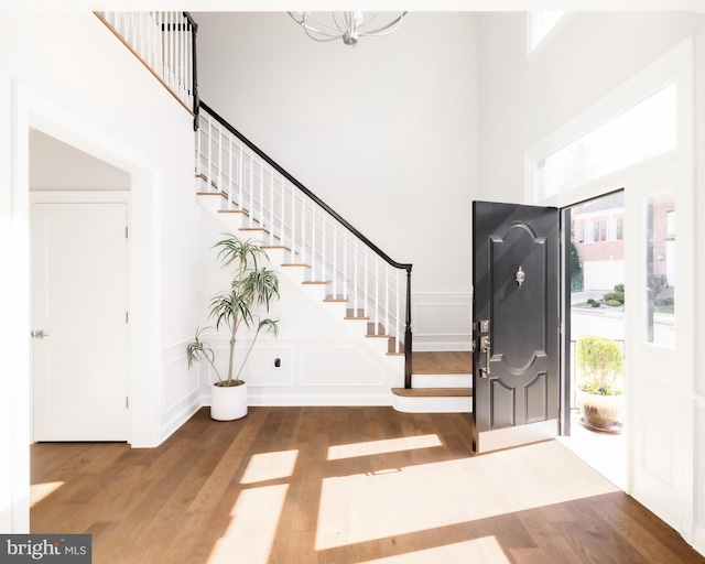 entryway with wood finished floors, a towering ceiling, and a decorative wall