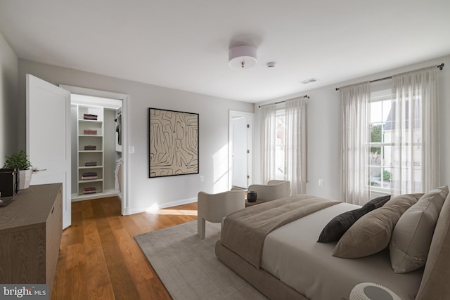 bedroom with visible vents, baseboards, a closet, a walk in closet, and light wood-type flooring
