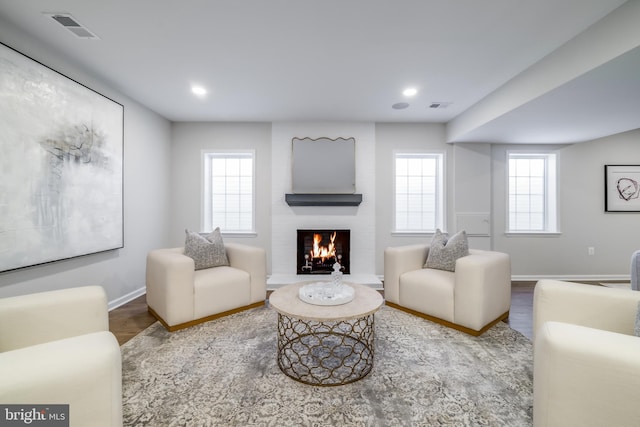 living area featuring a fireplace, wood finished floors, visible vents, and baseboards