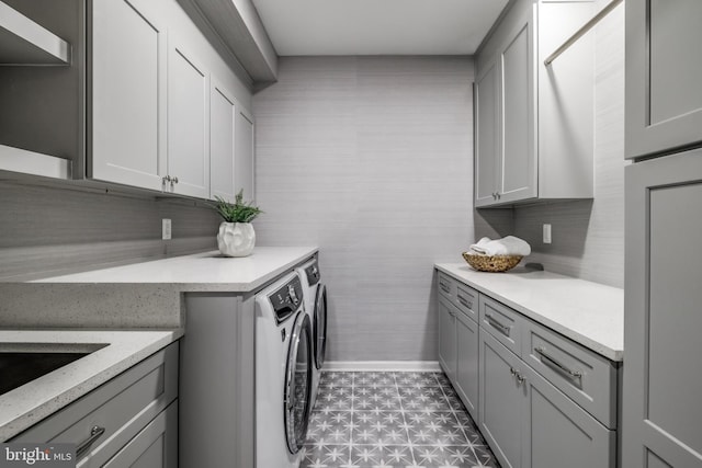 laundry area featuring baseboards, cabinet space, and washer and clothes dryer