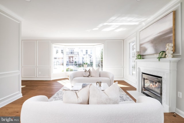 living room with a fireplace, a decorative wall, and wood finished floors