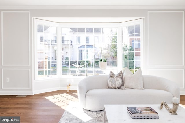 sitting room with visible vents, ornamental molding, baseboards, and wood finished floors