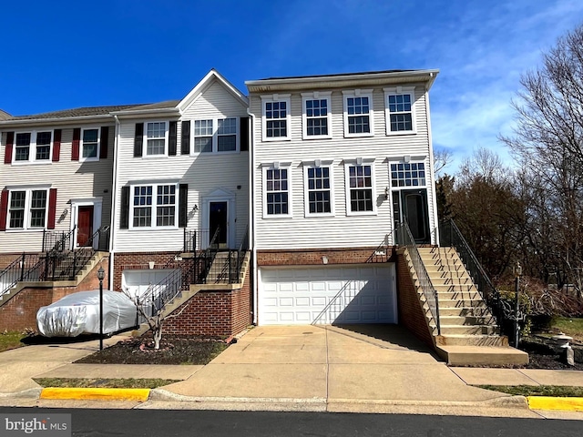 multi unit property featuring a garage, brick siding, driveway, and stairway