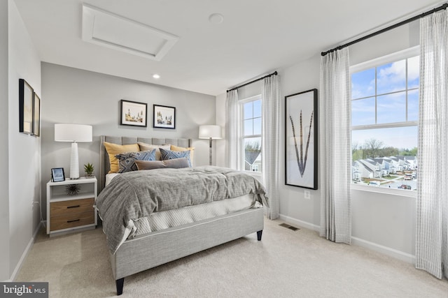 bedroom with visible vents, baseboards, attic access, and light colored carpet