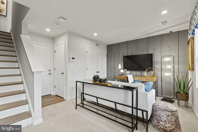 living area featuring recessed lighting, stairs, visible vents, and light colored carpet