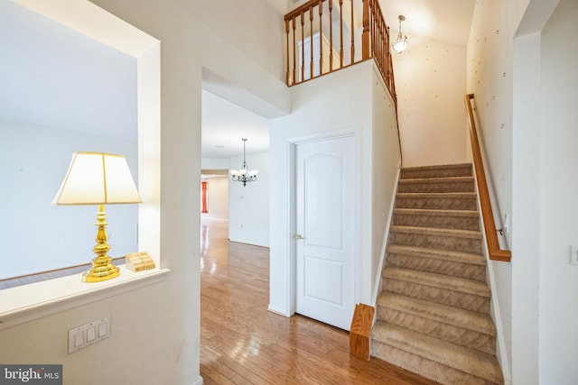 staircase with an inviting chandelier and wood finished floors