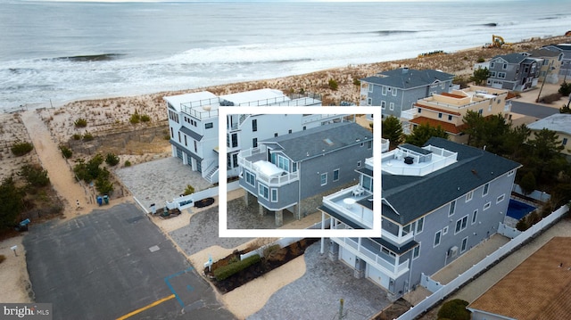 drone / aerial view featuring a view of the beach, a water view, and a residential view