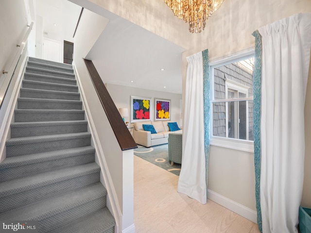 staircase with baseboards and a chandelier