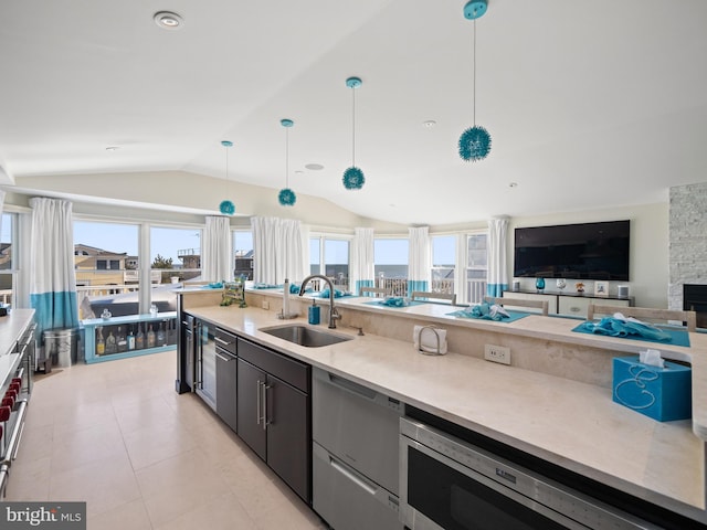 kitchen with open floor plan, vaulted ceiling, pendant lighting, a sink, and recessed lighting