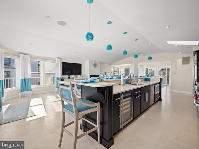 kitchen with visible vents, open floor plan, a sink, beverage cooler, and dark cabinetry