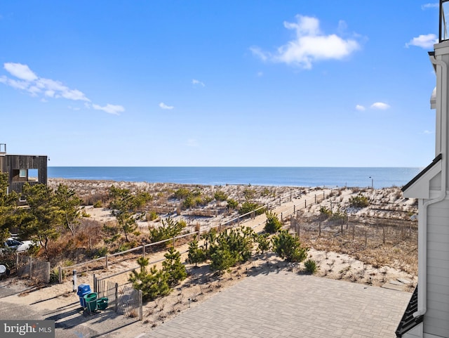 property view of water with fence and a beach view