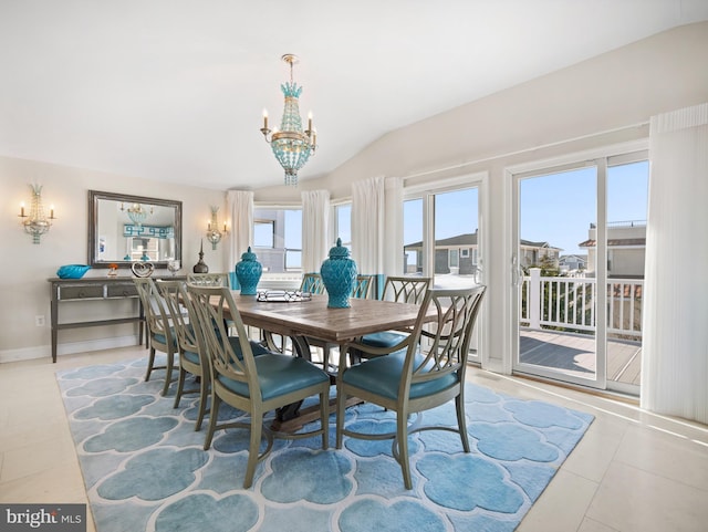 tiled dining room with a chandelier, vaulted ceiling, and baseboards