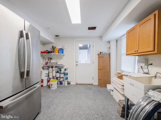 kitchen with carpet, baseboards, a sink, and freestanding refrigerator