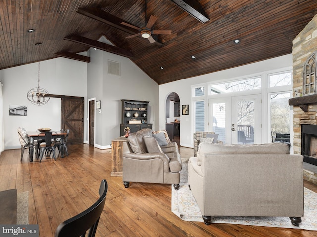 living room with high vaulted ceiling, a fireplace, visible vents, and hardwood / wood-style flooring