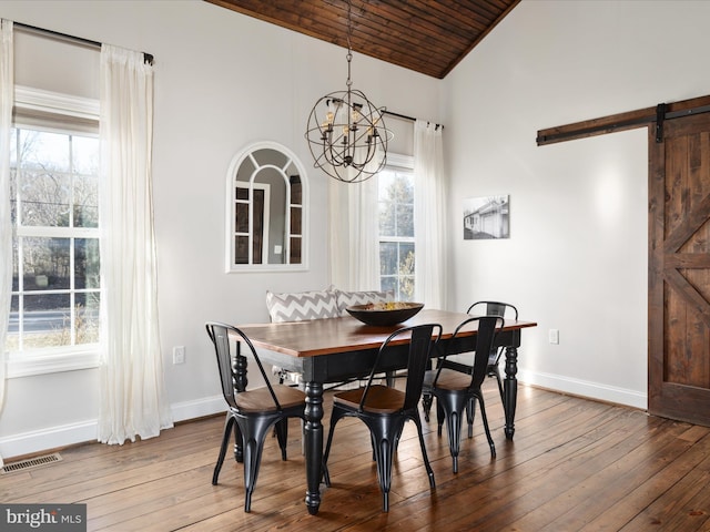 dining space with dark wood-type flooring, an inviting chandelier, baseboards, and a barn door