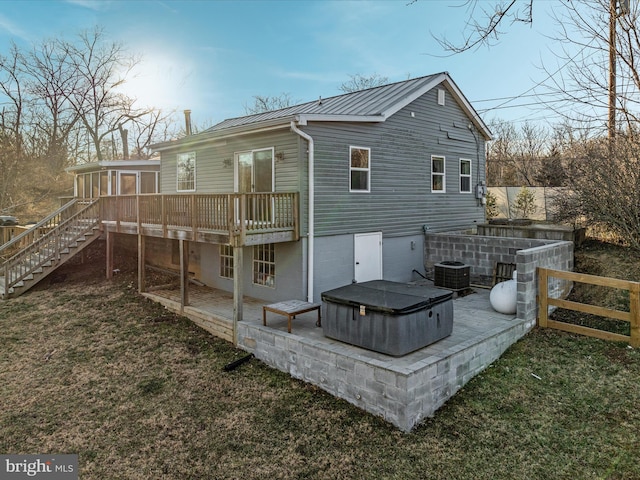 back of property with a hot tub, stairway, metal roof, a deck, and central AC