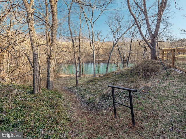 surrounding community featuring a water view and fence