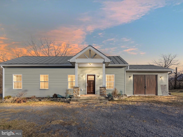 view of front of house featuring a garage, metal roof, a standing seam roof, and driveway