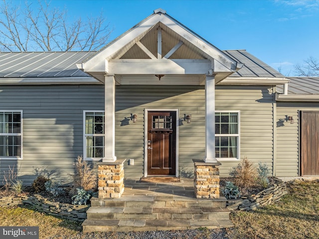 view of exterior entry with covered porch, metal roof, and a standing seam roof