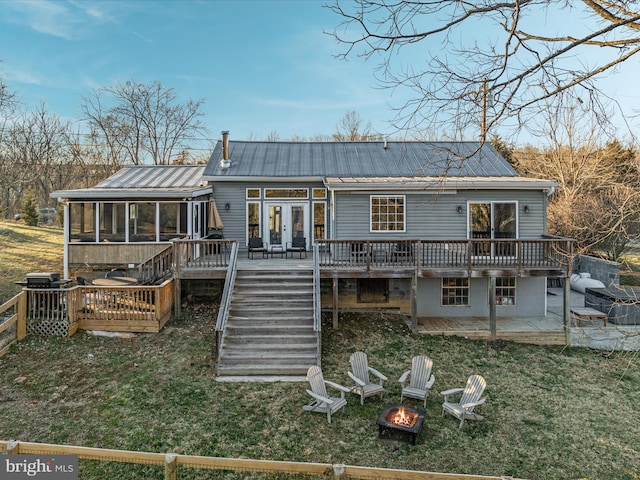 back of property featuring a wooden deck, a fire pit, a patio, and french doors