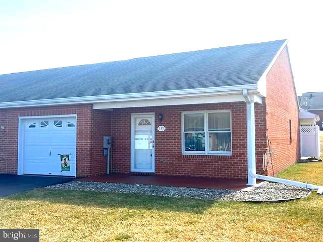 single story home featuring a garage, a front lawn, and brick siding