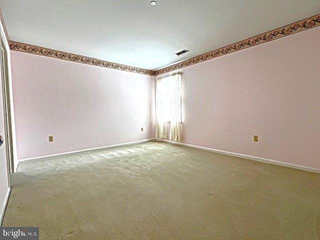 carpeted spare room with visible vents and baseboards