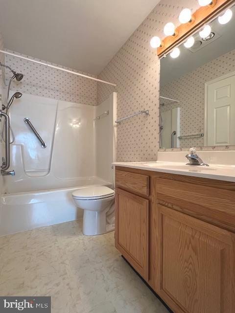 full bath featuring tub / shower combination, vanity, toilet, and wallpapered walls